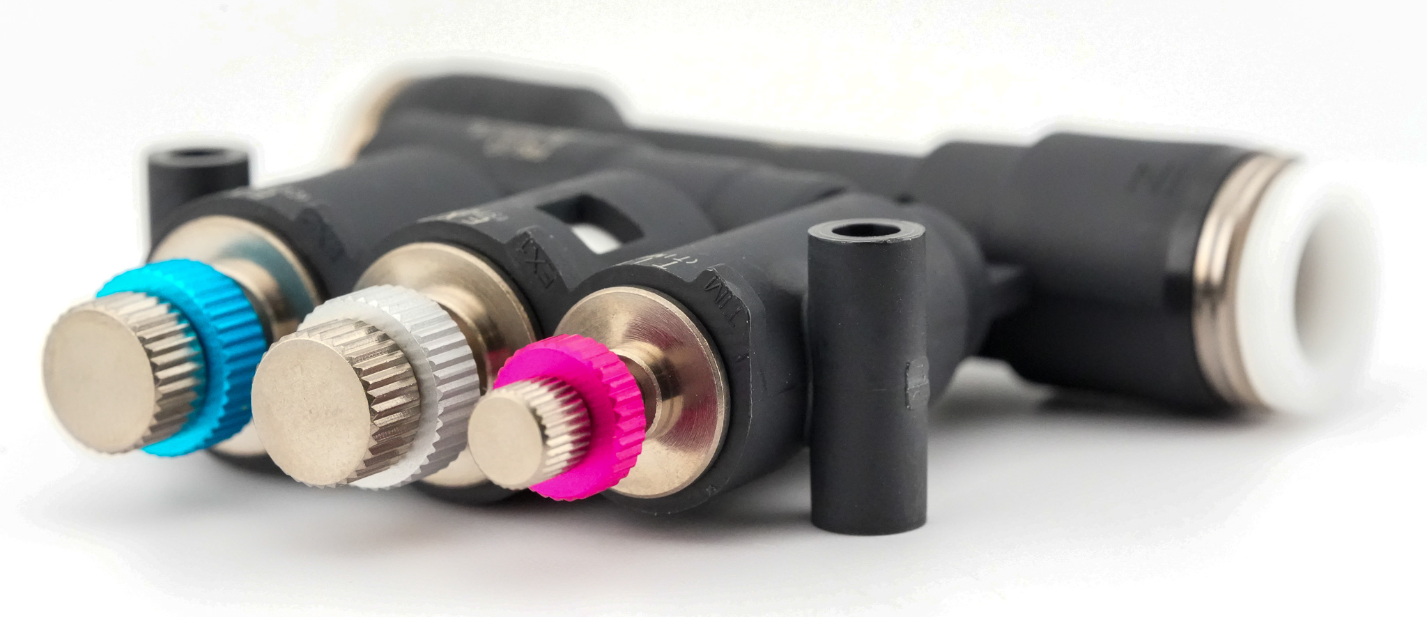 Close-up macro shot of BJSU three color-coded needle heads: blue EX2 (Cushion), silver EX1 (Speed), pink TIM (Timer)